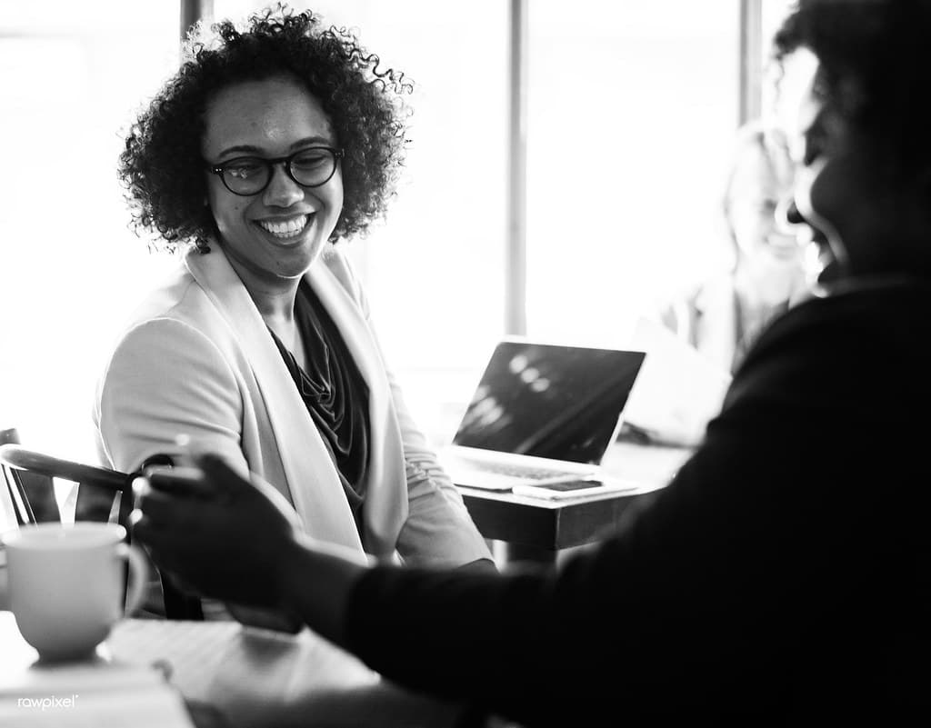 Black-and-white photograph of a smiling professional woman in a meeting